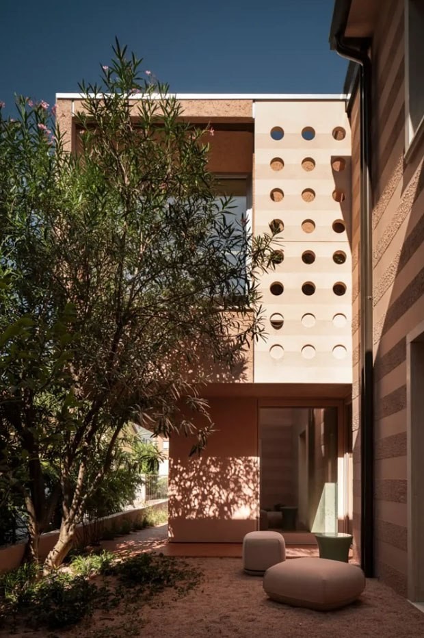 Перфорированный консольный вынос работает как важная климатическая и гражданская инфраструктура: он формирует крыльцо, защищает вход и выводит дом в сторону улицы.