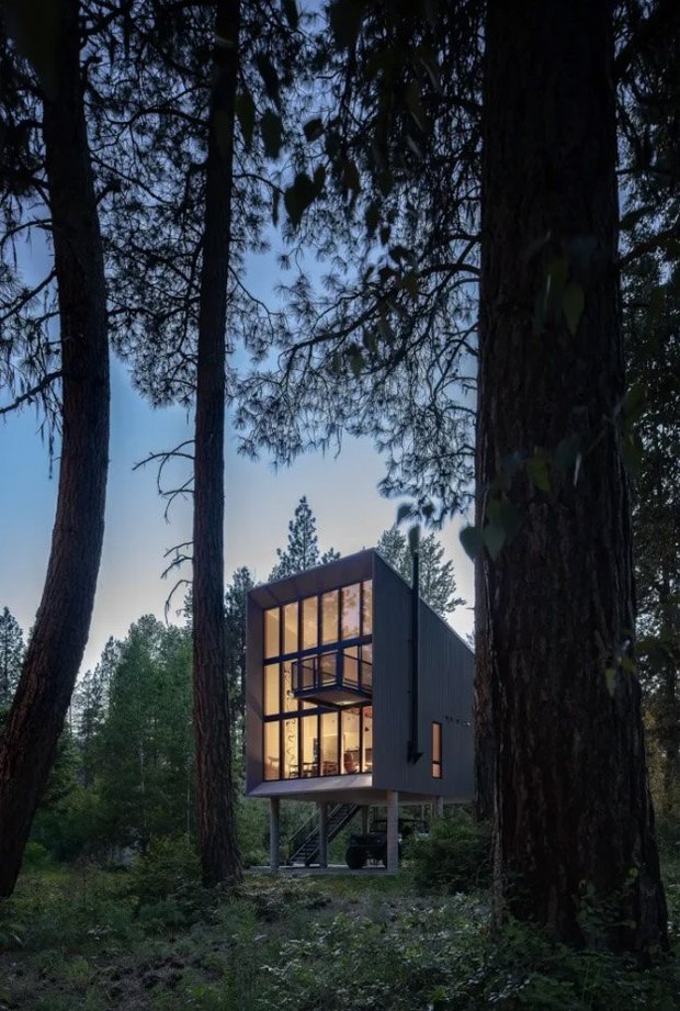 На закате 7-метровая стеклянная стена загорается как фонарь среди сосен, подчёркивая вертикальный объём дома.